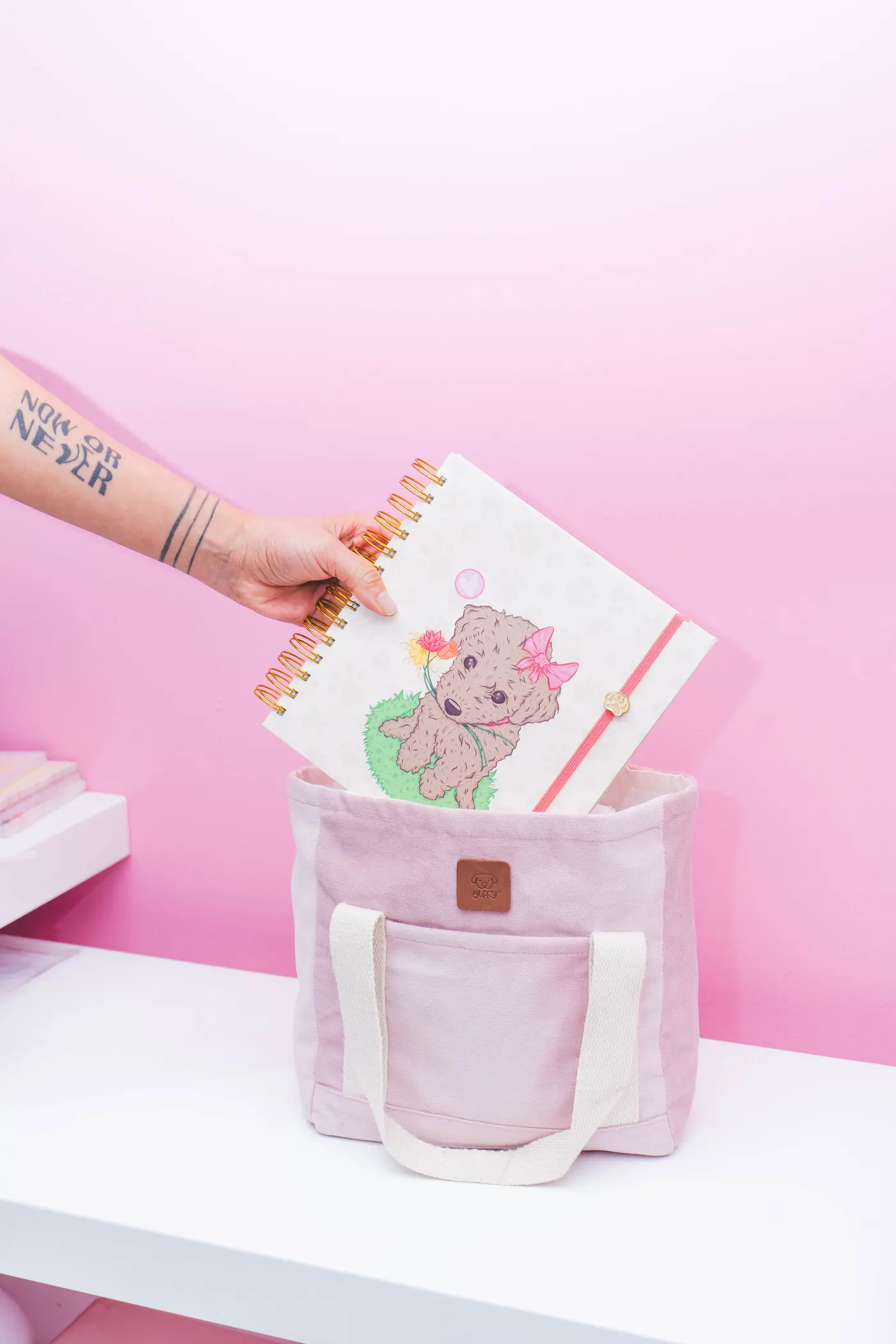 Cuaderno ilustrado de perrito OLFFY guardado en una tote bag rosada de algodón de la marca.