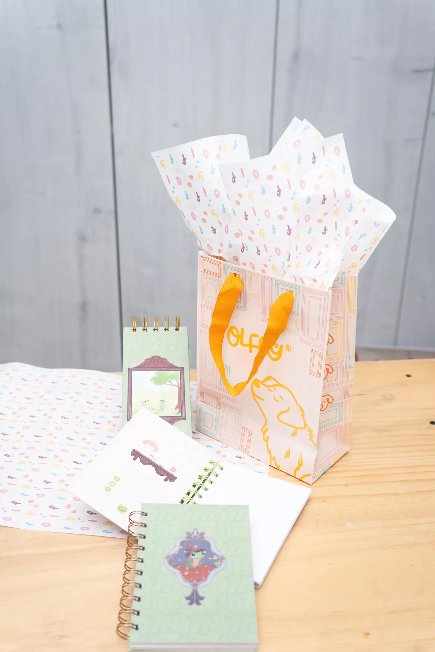 Bolsa de regalo OLFFY con papel de seda de la marca y cuadernos ilustrados, lista para regalar.